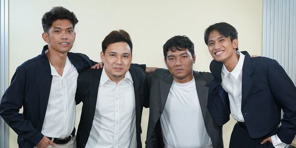 Four men posing together dressed formally.