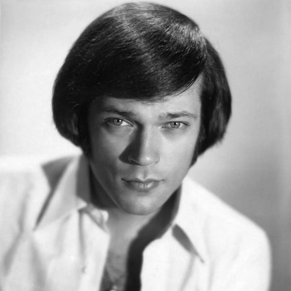 Black and white portrait of a young man with styled hair and intense gaze.