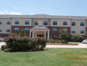 Exterior view of a three-story hotel building with landscaped greenery.