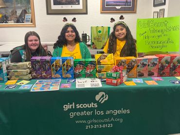 Three Girl Scouts selling cookies at a booth for Girl Scouts Greater Los Angeles.