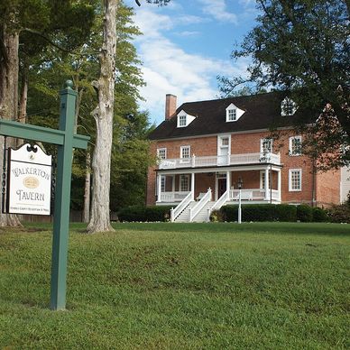 Historic brick tavern with a welcoming porch and green lawn.