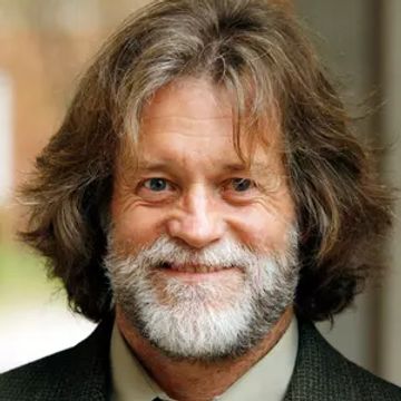 Smiling man with long hair and gray beard.