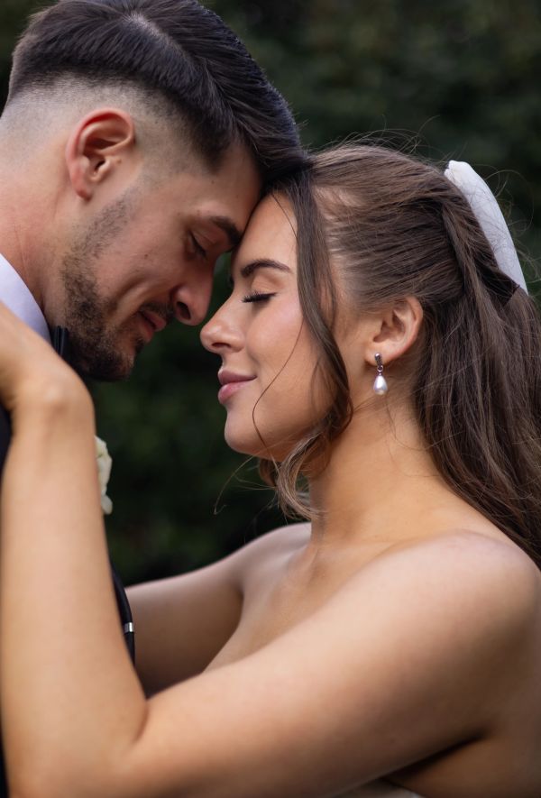 A tender moment between a bride and groom with foreheads touching.