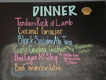 Chalkboard menu featuring diverse dinner options like Tandoori Lamb and Coconut Grouper.