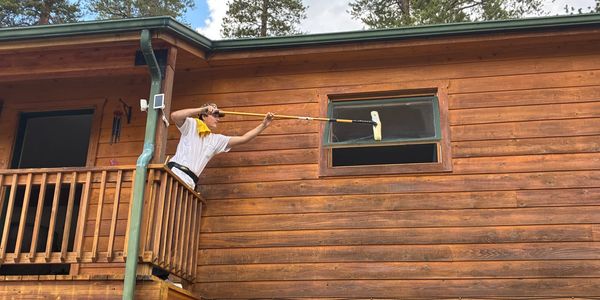 Person cleaning a cabin window from a balcony using a mop.