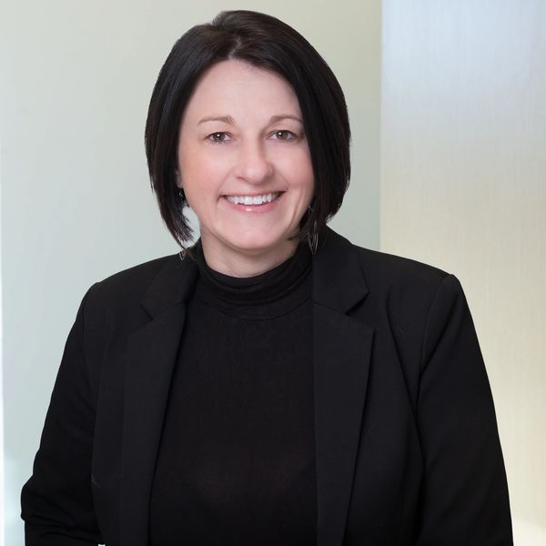 Professional woman in black blazer smiling at the camera.