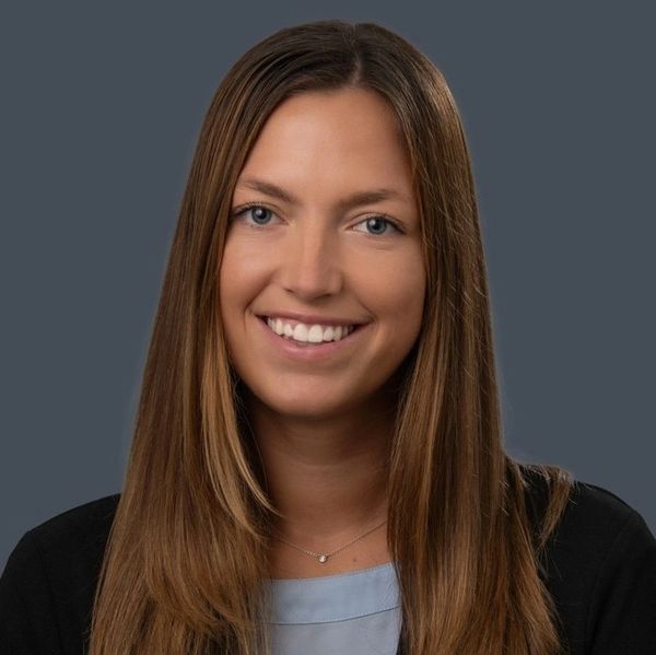 Professional portrait of a young woman with long brown hair and a friendly smile.