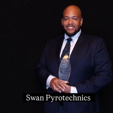 Man in suit holding an award with 'Swan Pyrotechnics' text.