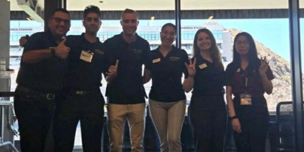 Group of six people posing indoors, making hand gestures.
