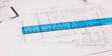 A blue ruler placed on architectural blueprints for precise measurements.