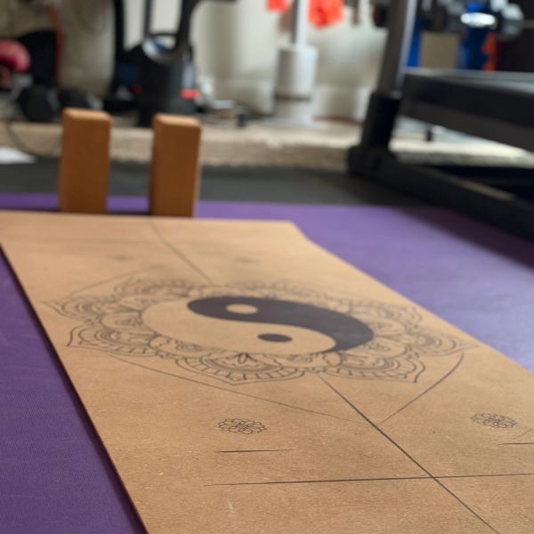 Yoga mat with yin-yang design on purple floor.