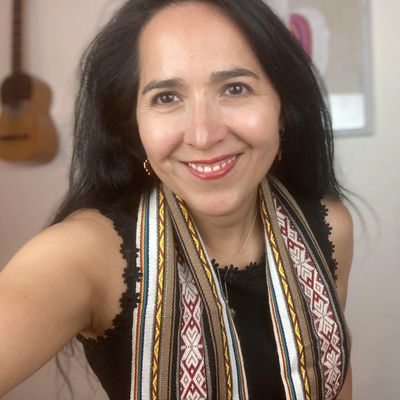 Woman smiling warmly wearing a patterned scarf and black top.
