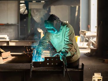 Representative stock photograph of a welder working on metal.