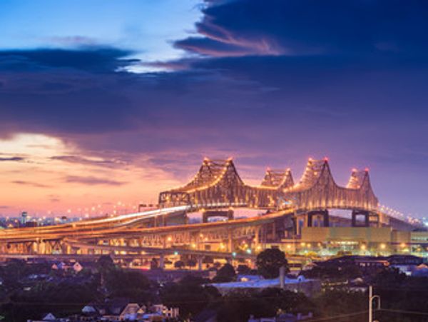 Bridge illuminated at twilight with cityscape.