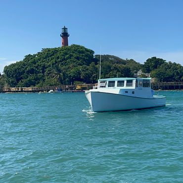 Boat on water near a lighthouse on a sunny day.