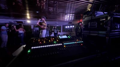 Audio tech at a lit mixing console running sound and playback during a live show