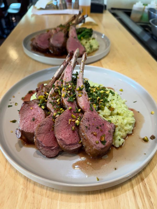 Plated rack of lamb with risotto and herbs.
