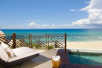 Lounge chair next to plunge pool overlooking tropical beach and sea on a sunny day. 