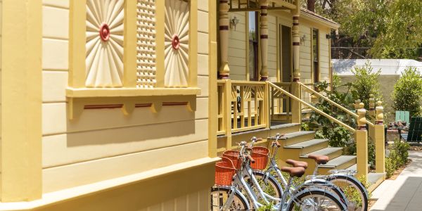 Two bicycles parked outside a yellow wooden house.