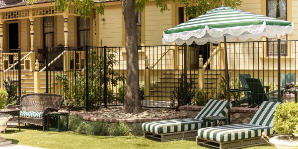 Backyard with two striped lounge chairs and a big umbrella.