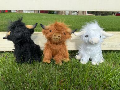 Three plush highland cows in black, brown, and white.