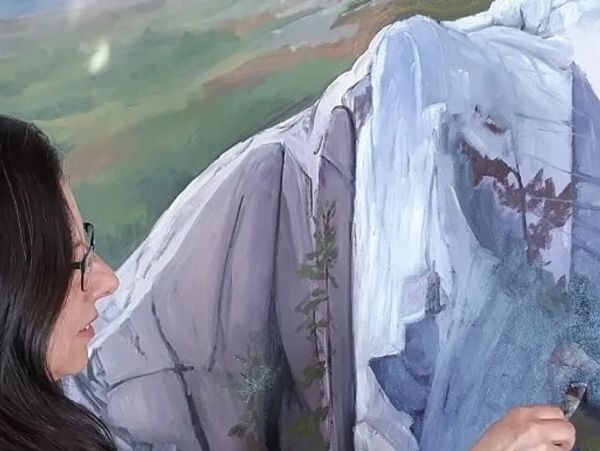 Woman painting a realistic mountain landscape.