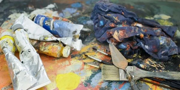 Artist's paint tubes, brushes, and cloth with paint stains.