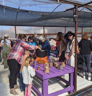 People gathered around a purple table participating in an outdoor workshop.