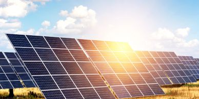 Solar panels in a field under a partly cloudy sky.