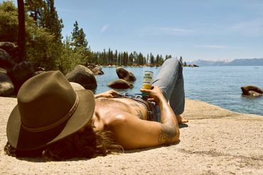 Person relaxing by the lake with a can of drink.