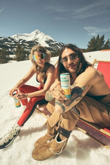 Two people enjoying sun and snow with sunscreen in the mountains.