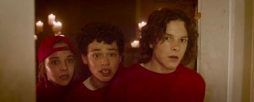 Three teens in red looking surprised or scared indoors.