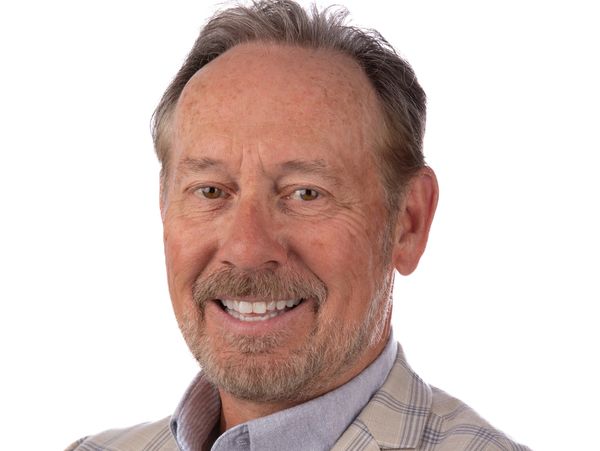 Smiling middle-aged man in a plaid blazer against a white background.