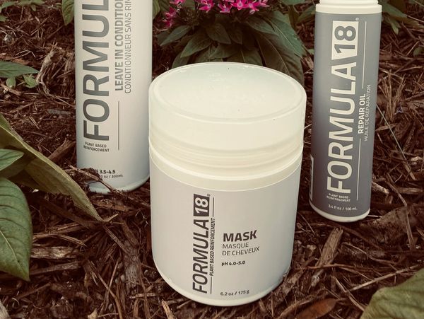 Hair care products from Formula 18 on soil with plants.