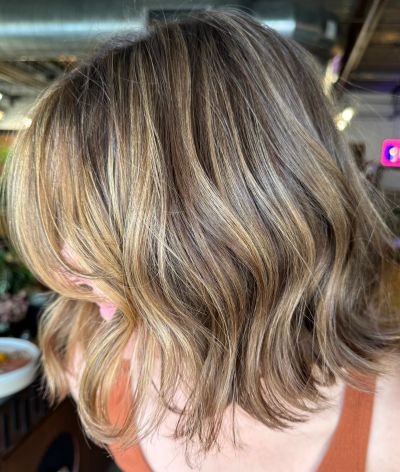 Wavy shoulder-length hair with blonde highlights.