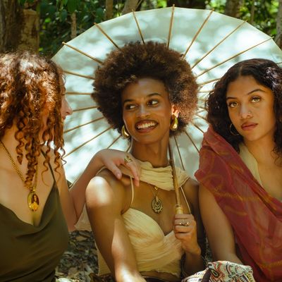 Three women enjoying a sunny day with an umbrella.