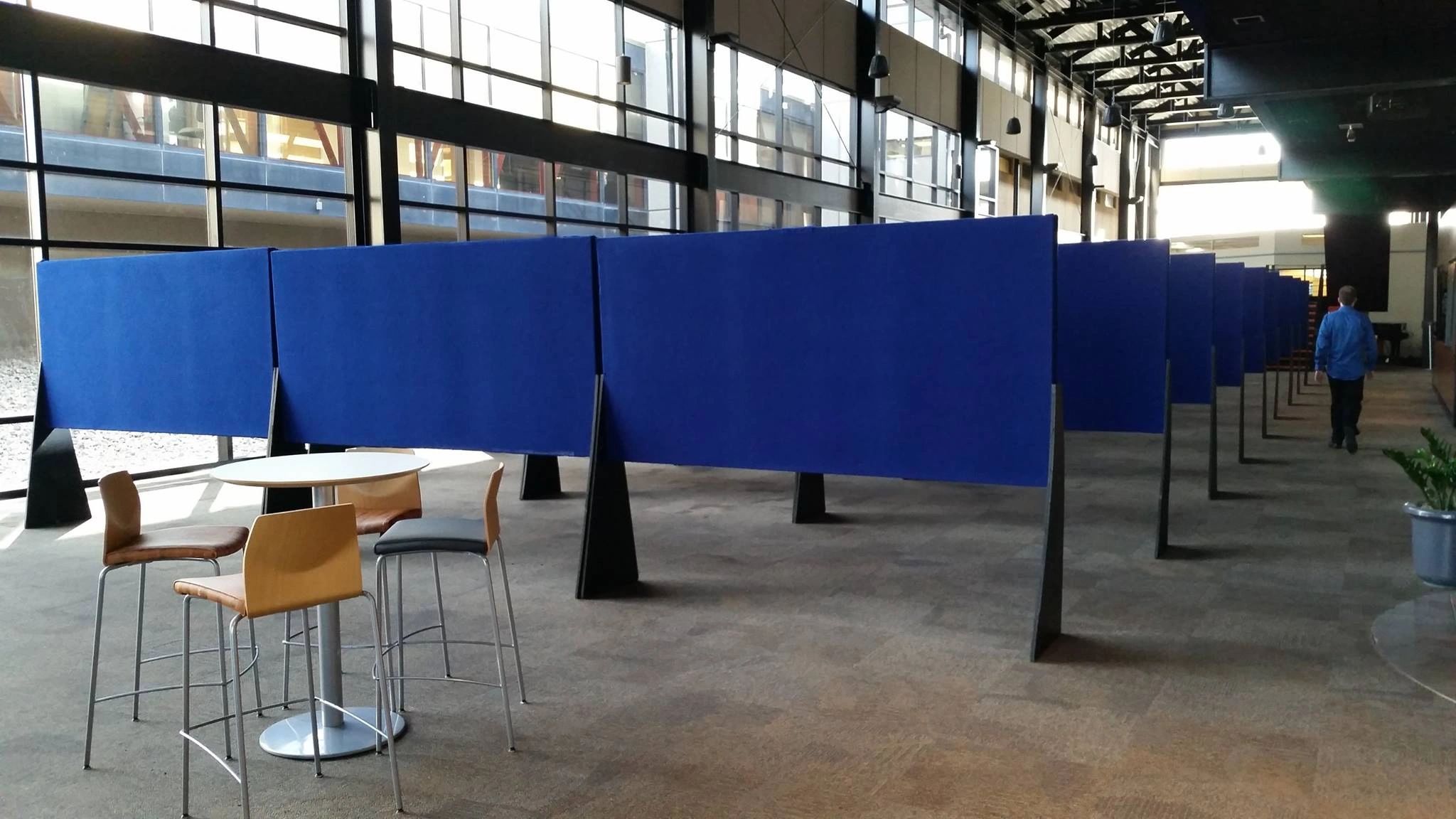 Rental blue fabric covered panels horizontal on legs to be used for poster and literature attachment