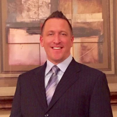 Man in a suit and tie smiling indoors.