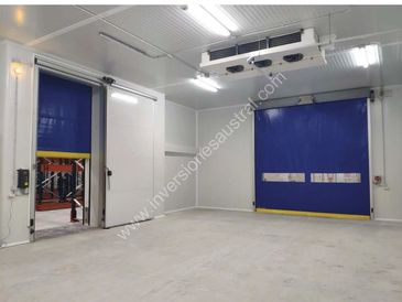Interior of a clean industrial cold storage room with blue roll-up doors.