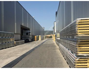 Industrial warehouse area with stacked pallets and a truck.