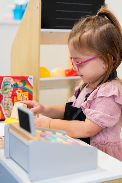 A young girl playing with a toy cash register.