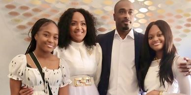 A family of four dressed elegantly, smiling together indoors.