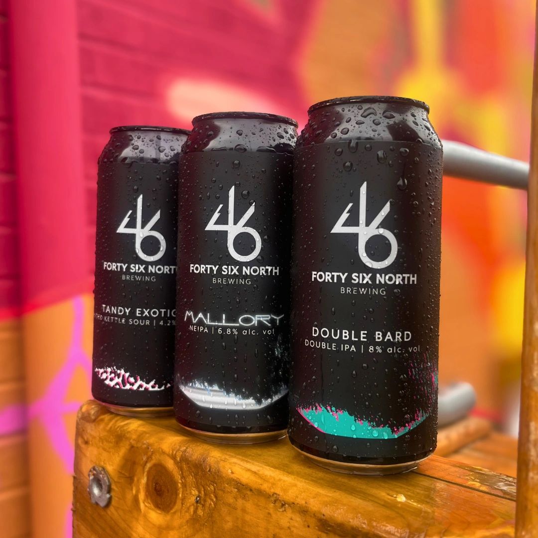 Three cold cans of Forty Six North Brewing beer with condensation on them.