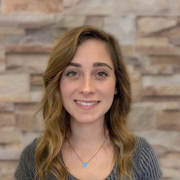 Young woman smiling in front of a stone wall.