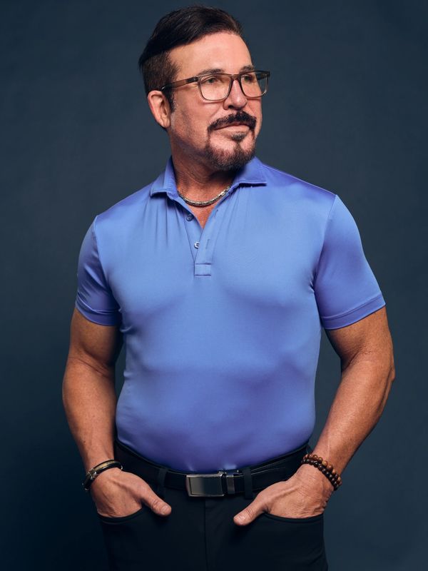 Man in blue polo shirt posing confidently.
