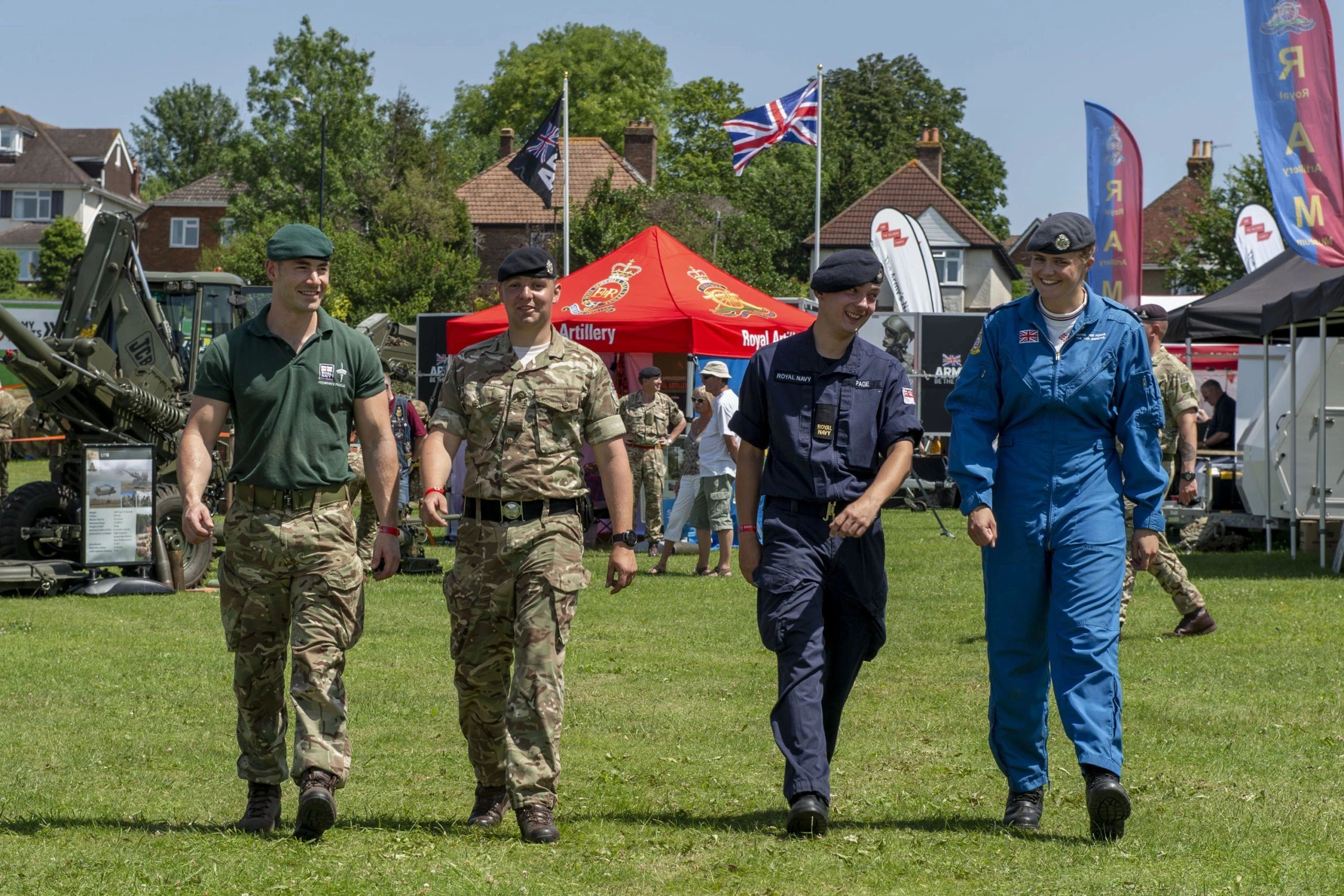 Four military personnel walking at a public event.