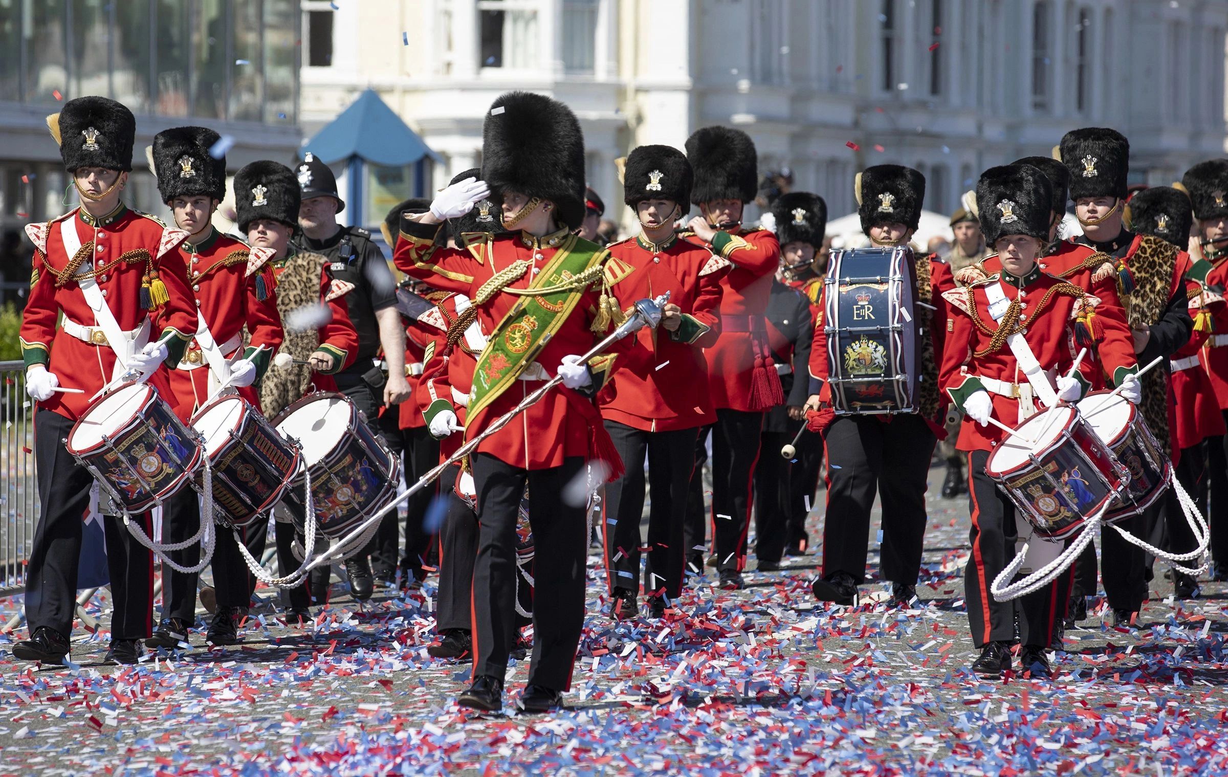 British military band marching in parade with confetti.