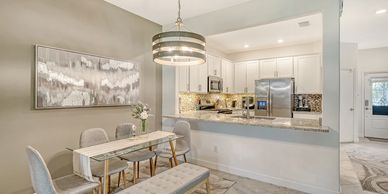 Modern dining area with glass table and open kitchen with white cabinets.