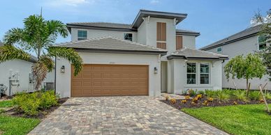 Modern two-story house with a spacious driveway and tropical landscaping.