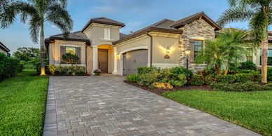 A modern suburban house with a paved driveway and lush landscaping.